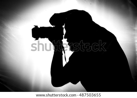 Silhouette of photographer taking pictures in studio with backlight