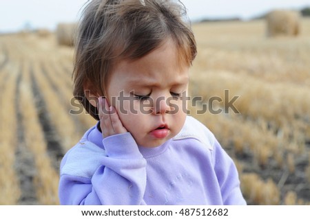 Little girl with ear pain moaning holding hand on ear, child headache pain, health care concept, ear protection from cold, kid catch cold in cold season, hearing loss, Royalty-Free Stock Photo #487512682