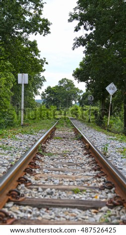 Kanchanaburi, Thailand - Death Railway. Seemingly end of track but actually a left turn. Road sign on the right in Thai translates to "normal". Focus is on "end of road" (center patch of grass).