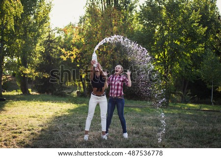 funny girls traveling and fooling around in the park. Spill water from a bottle.