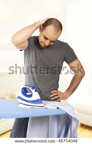 young man try to ironing his clothes without success
