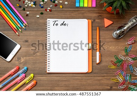 Title To do and Business (school) accessories (notebook, diary, mobile phone, cactus, pens, pencils) on a wooden table. Top view.