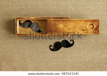 Hipster background. Fancy mustache in an old box. Tweed fabric. Vintage style.