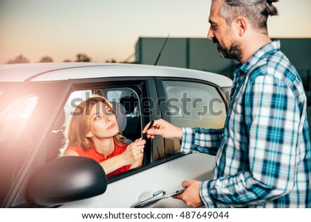 Woman sitting in the car and signing car rental agreement