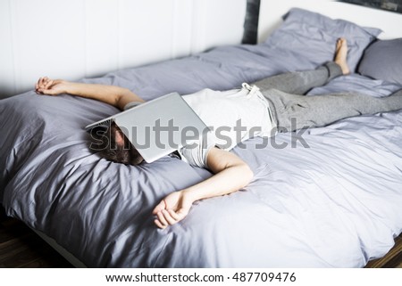 A man sleeping over laptop computer in bed Royalty-Free Stock Photo #487709476