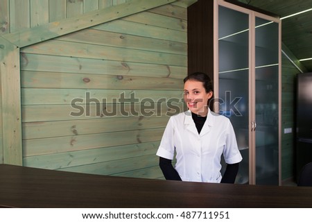 Woman on receptrion smiles and welcomes the virtual visitor at spa or modern clinic. Papers with agreement in your hand.