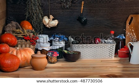Domestic stocks with marinated vegetables in glass jars on a wooden shelf. Pantry. Pumpkins, dishes, boxes, old things. Many items