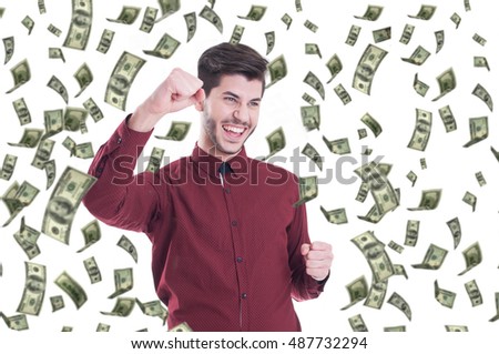 Happy man exults pumping fists ecstatic celebrates success screaming under money rain. Falling down dollar bills banknotes 