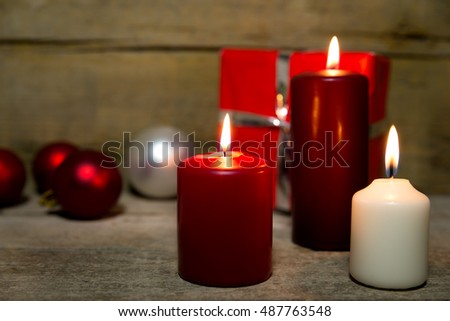 Candles, christmas balls and a red gift on wooden table, wooden background
