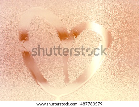 Rose gold color heart shape color, water drop on glass. Illuminate background.