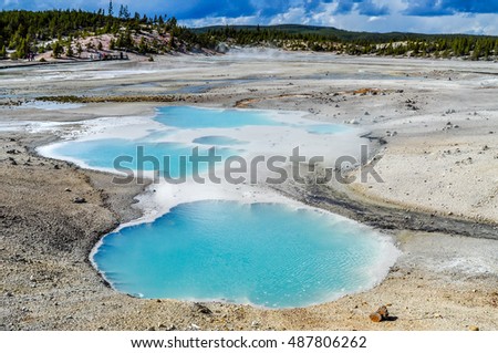 Pools of colorfully colored water dot the landscape of the Norris Geyser Basin in Yellowstone National Park. Royalty-Free Stock Photo #487806262
