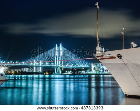 Ship on the background of night city and the cable-stayed bridge. Night lighting of the city.