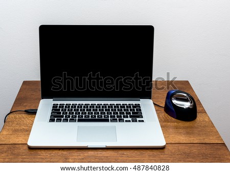 Laptop with blank screen on table with a vertical mouse