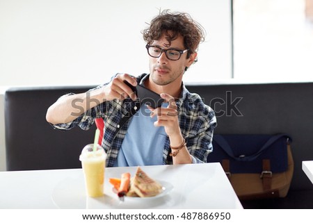 leisure, food, eating and people concept - man with smartphone photographing his lunch at cafe