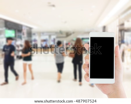 woman use mobile phone and blurred image of people in the mall