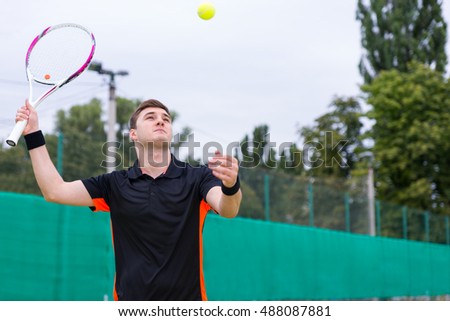 Athletic male tennis player wearing a sportswear in action during a match at tennis court at early morning
