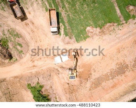 Aerial shot of excavator machine loads a dump truck on harvest field