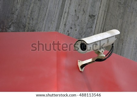 Old security camera outside building on the wall.