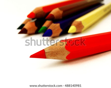 red colored pencil in front of other pencils on white background, macro, shallow depth of field