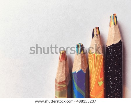 Colorful rainbow pencils in a row lay on white paper. Vintage photo with retro style tonal filter effect