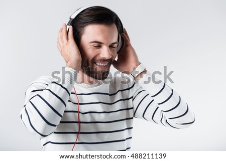 Glad bearded man listening to music.