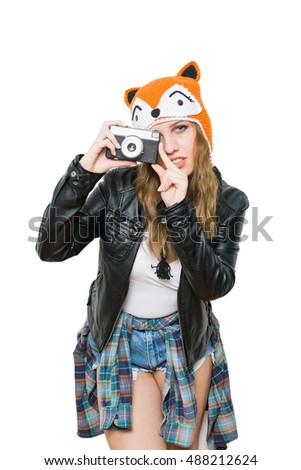Portrait of modern beautiful millennial teenage girl in cool funny knitted fox beanie hat using analogue camera. Cool young female photographer. Isolated on white background, mild retouch.