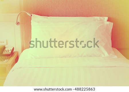 lamp and white pillow on bed in hotel.