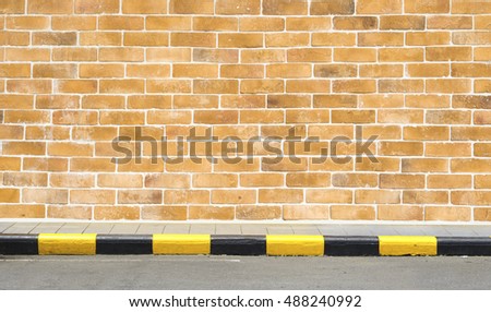brick wall with footpath black, yellow traffic sign background