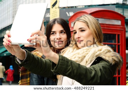 Portrait of two young girlfriends taking selfie with tablet on a trip together. Tourism concept. Outdoors.
