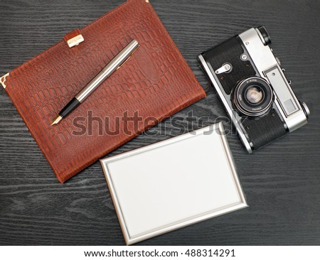 Photo, vintage camera and a notebook on a wooden table