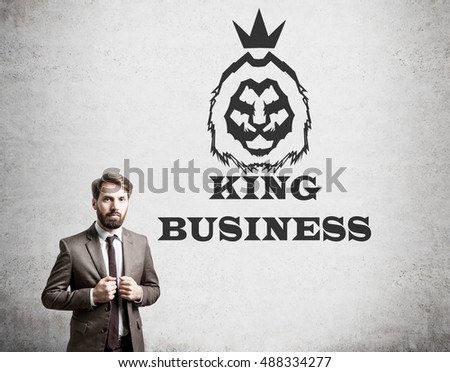 Businessman in brown suit is standing near concrete wall with king of business sketch on it. Concept of serious business