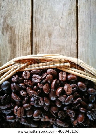 Coffee beans in a bamboo bowl on wood background