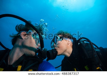 Couple of scuba divers kissing each other underwater