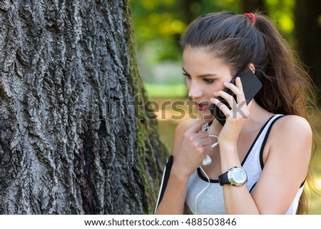 Portrait of Beautiful Young Woman Athlete Talking on Phone at the City Park before Running.