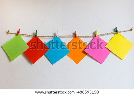 Post it paper note hanging on white wall background / Post it colorful paper notes hanging on the wall.