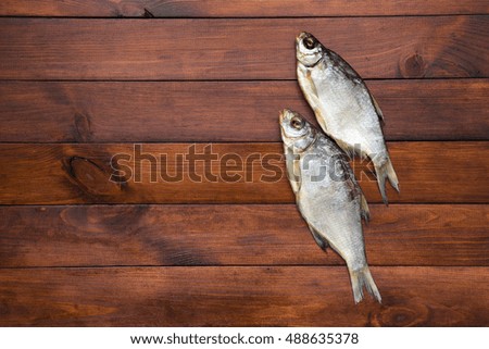 two  dried fish on a light brown wooden background with empty space