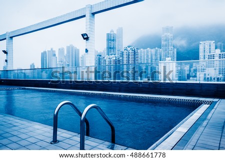 swimming pool at roof with hong kong residential apartments background,china.