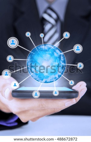 Close up of businessman hand holding a smartphone with social network icon on the screen