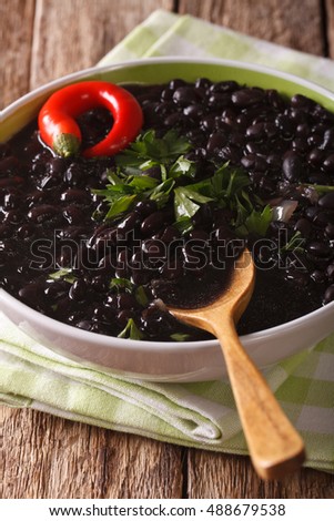 Stewed spicy black beans close up in a bowl on the table. vertical
