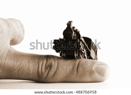 Miniature model of steam locomotive railroad in action of climbing man finger put on isolated white background scene represent the miniature railroad model toy and transportation concept related idea.