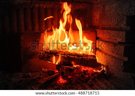 Burning fireplace. Burning wood in brick fireplace. Fireplace with a blazing fire. Fire in a fireplace. Hot fire in darkness on fireplace. Burning and glowing pieces of wood in Fireplace.