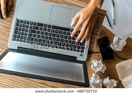 A man working with laptop on messy work space
