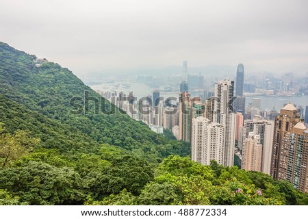 High view cityscape of modern city with green Forest and mist in hong kong. 
cohabitation Between nature and city.