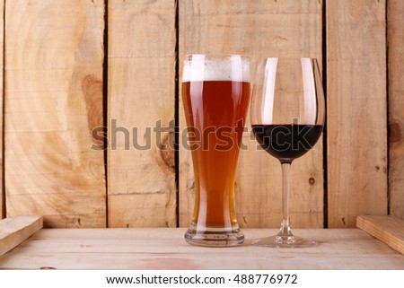 Tall glass of light beer and red wine glass over a textured wood background Royalty-Free Stock Photo #488776972