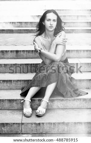 Young French girl sitting on the stairs in the Park. monochrome