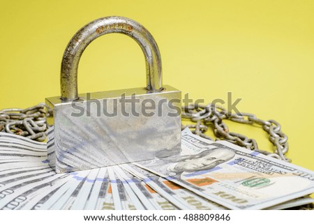 Dollars and a big silver lock on green background. copy space.