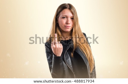 Teen girl making horn gesture over ocher background