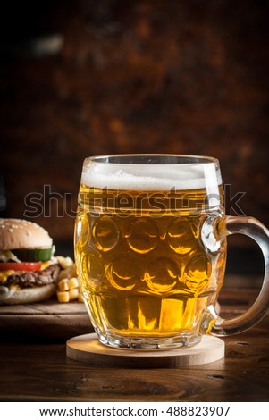 A glass of fresh cold light beer with gourmet hamburgers and wheat in a bar and a dark pub
