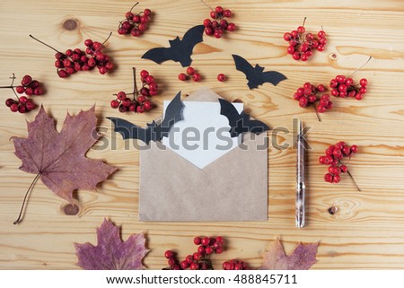 Top view of a Halloween wooden desk with paper, pen, envelope, bats, berries and maple leaves. With copy space.