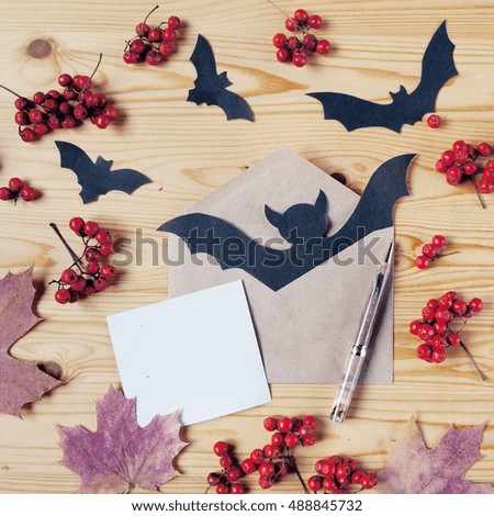 Top view of a Halloween wooden desk with paper, pen, envelope, bats, berries and maple leaves. With copy space